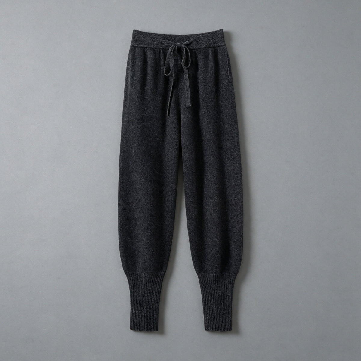 Cashmere drawstring trousers in charcoal black, front view, on a grey studio backdrop