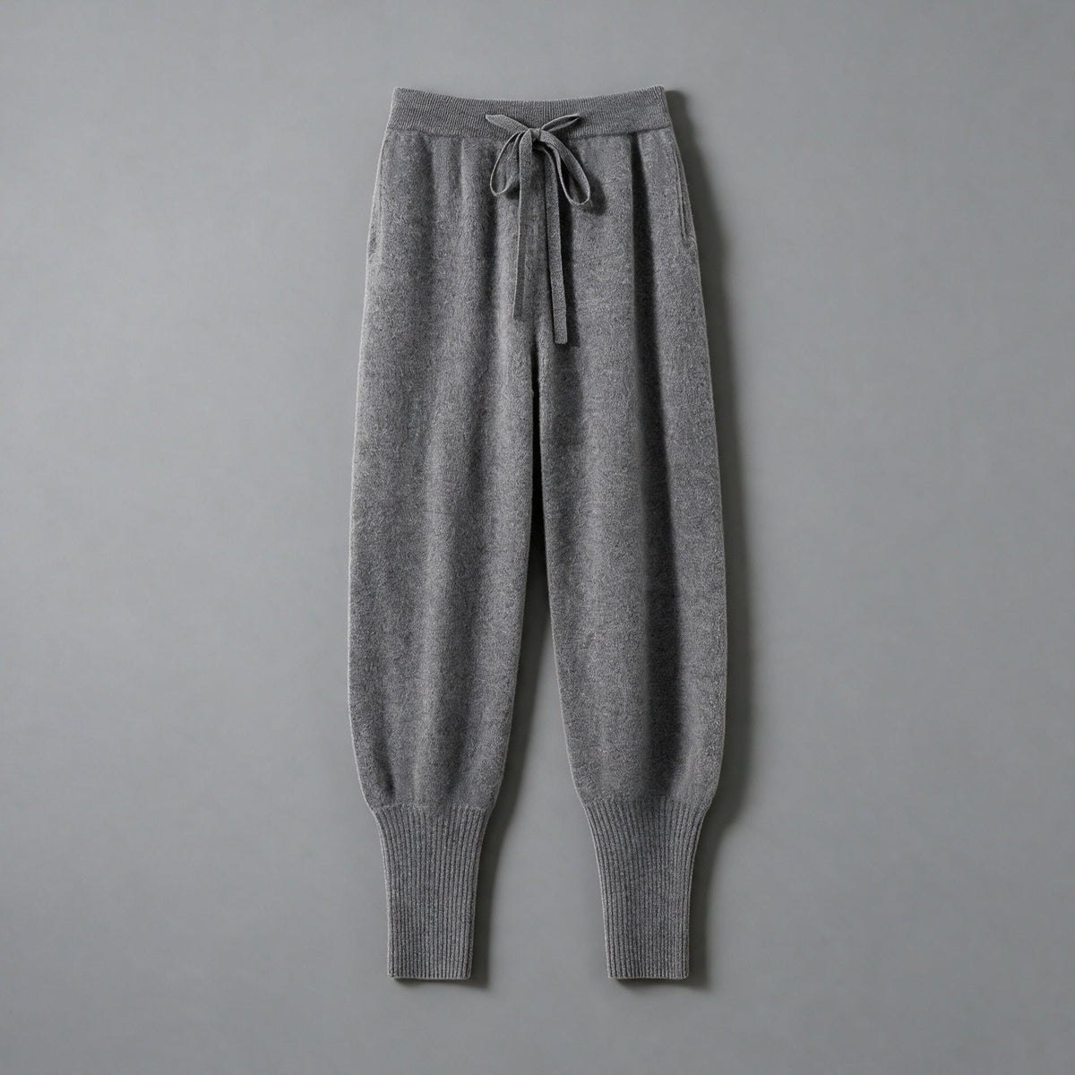 Cashmere drawstring trousers in mid grey, front view, on a grey studio backdrop