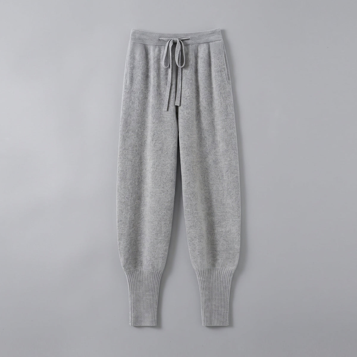 Cashmere drawstring trousers in light grey, front view, on a grey studio backdrop