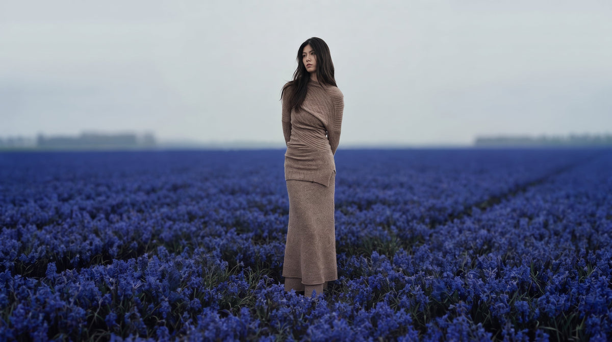 Woman in the Asymmetrical Mohair & Lambswool Knit Skirt and Top standing in a lavender field under a grey sky