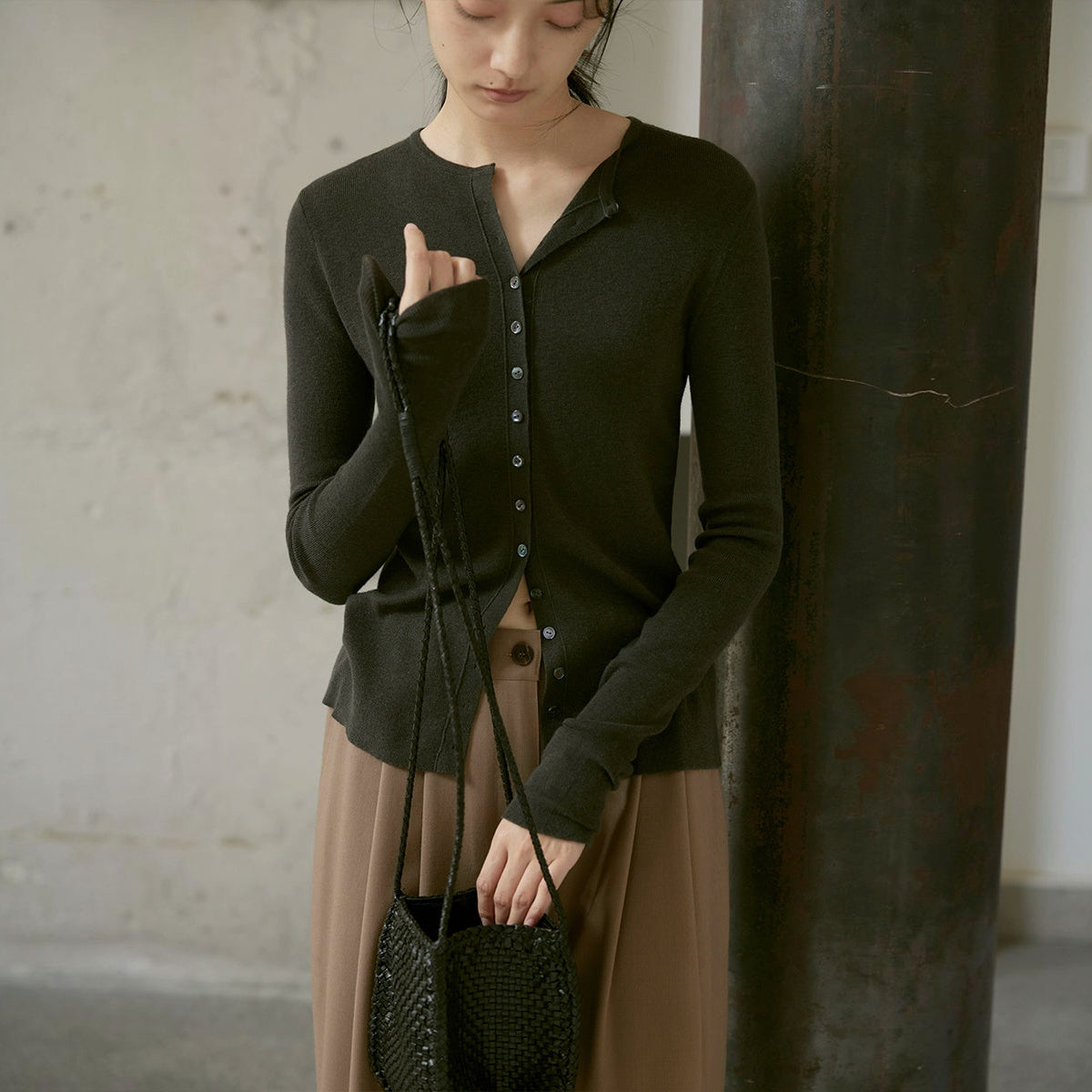 Wool cardigan in dark olive, square crop with a small woven bag