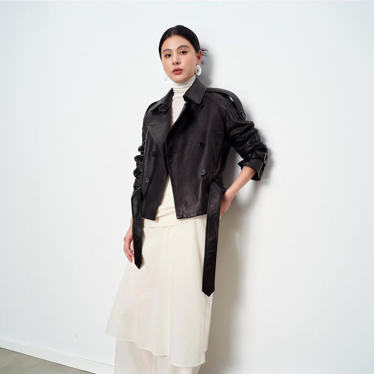 Vegetable-tanned sheepskin leather jacket in black, side view, worn over cream