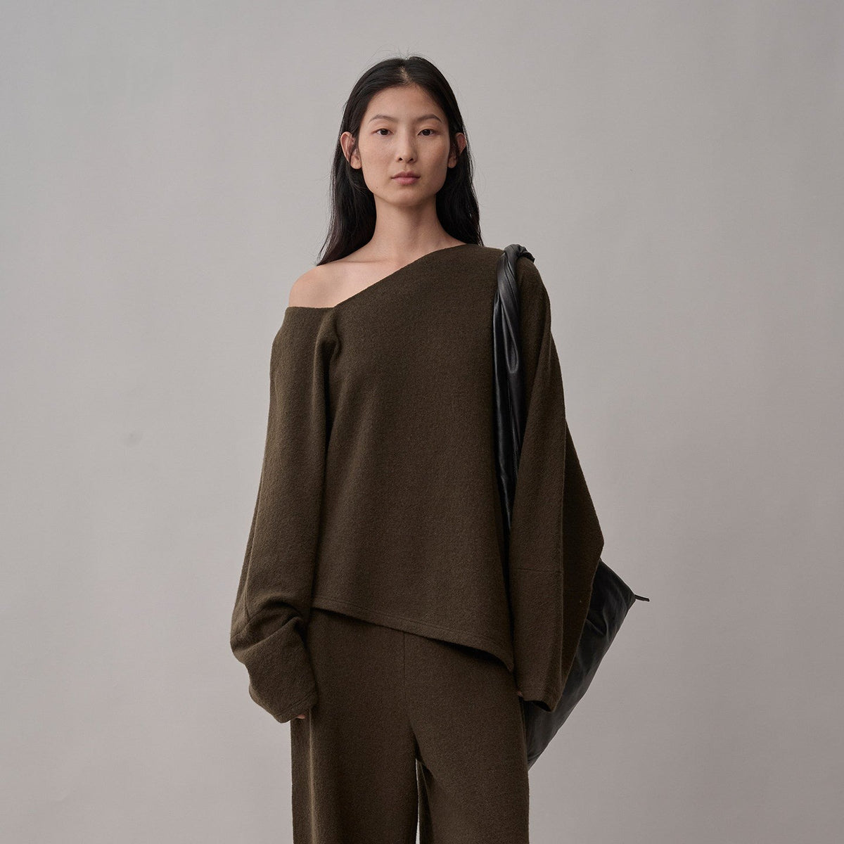 Dark brown wool sweater with an asymmetric neckline and hem, upper-body view on model