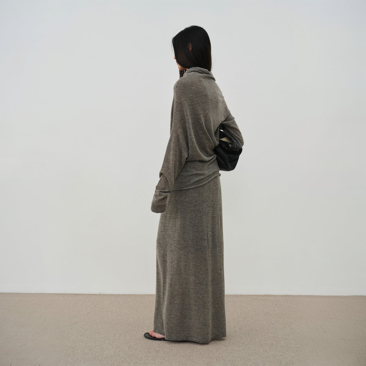 Brown cowl neck sweater and long knit skirt, back three-quarter view on model
