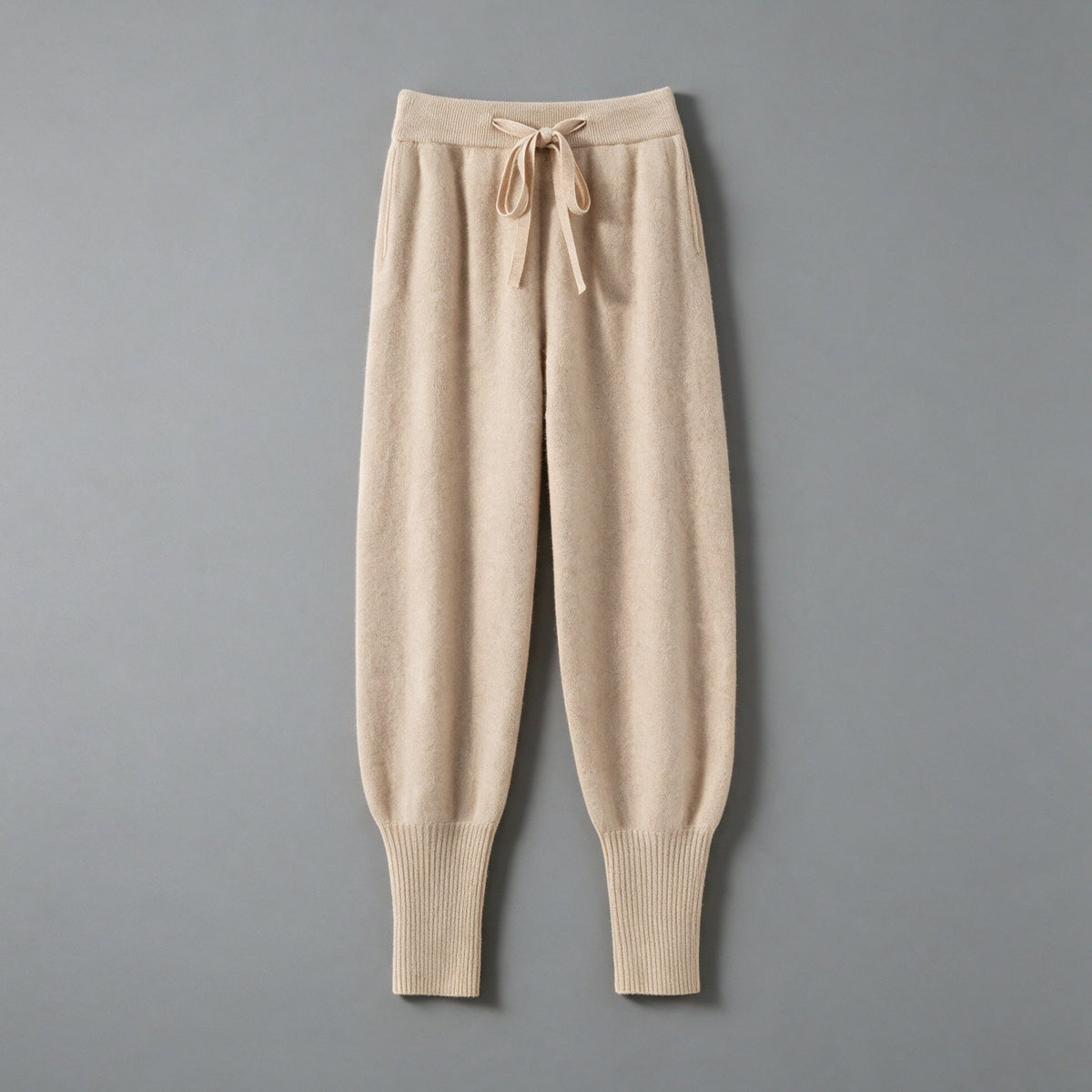 Cashmere drawstring trousers in beige, front view, on a grey studio backdrop