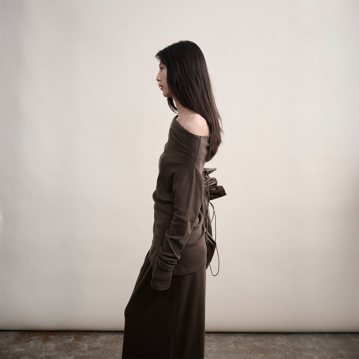 Brown cotton one-shoulder top with long sleeves, side profile on model