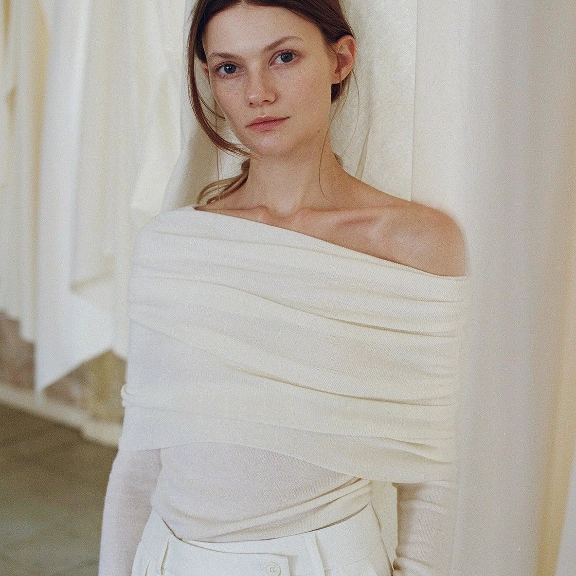 Off shoulder sweater in white, close crop of the folded neckline across the bust and one bare shoulder