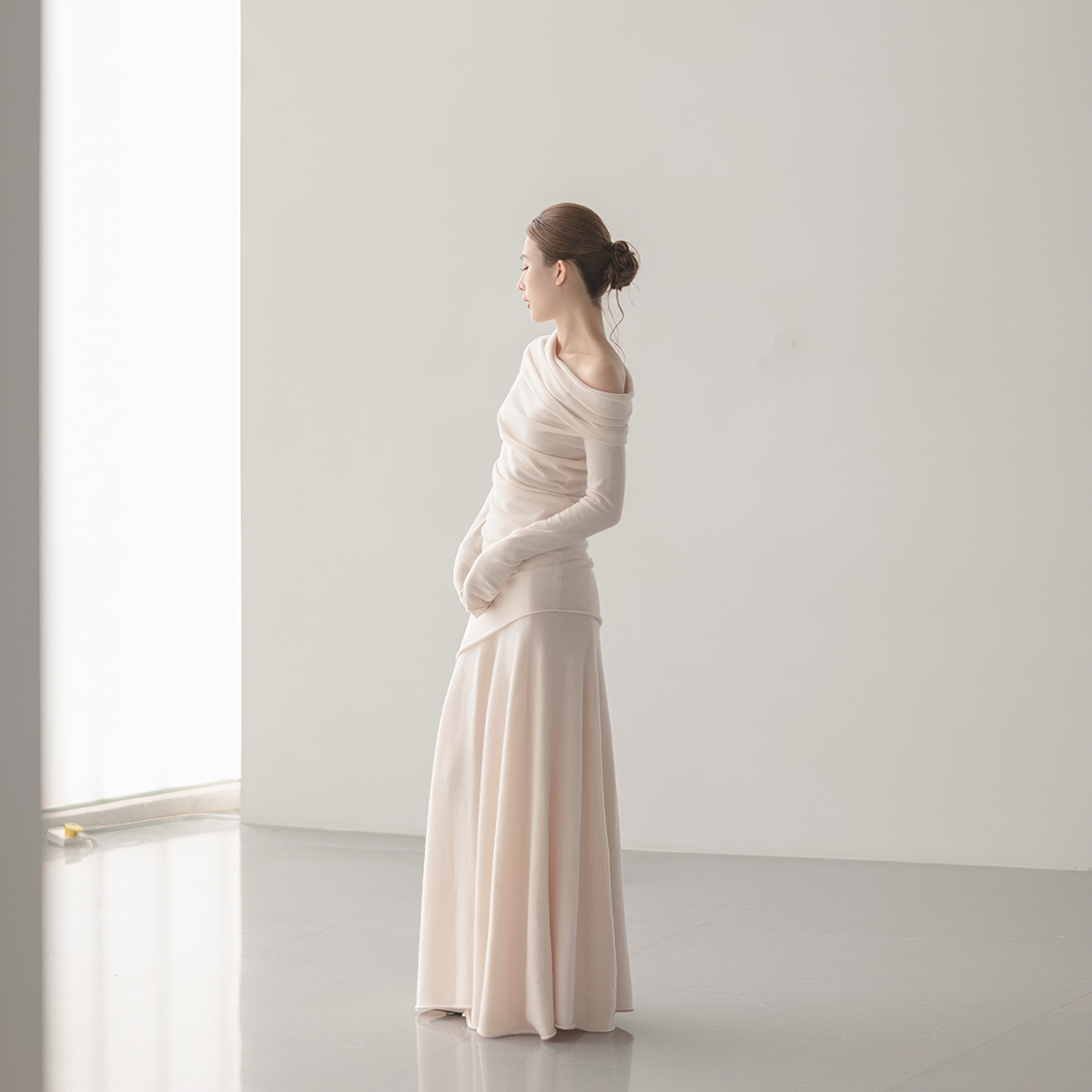 pale pink off-shoulder top and A-line skirt set, side view on model, folds at the neckline and a curved hem on the top