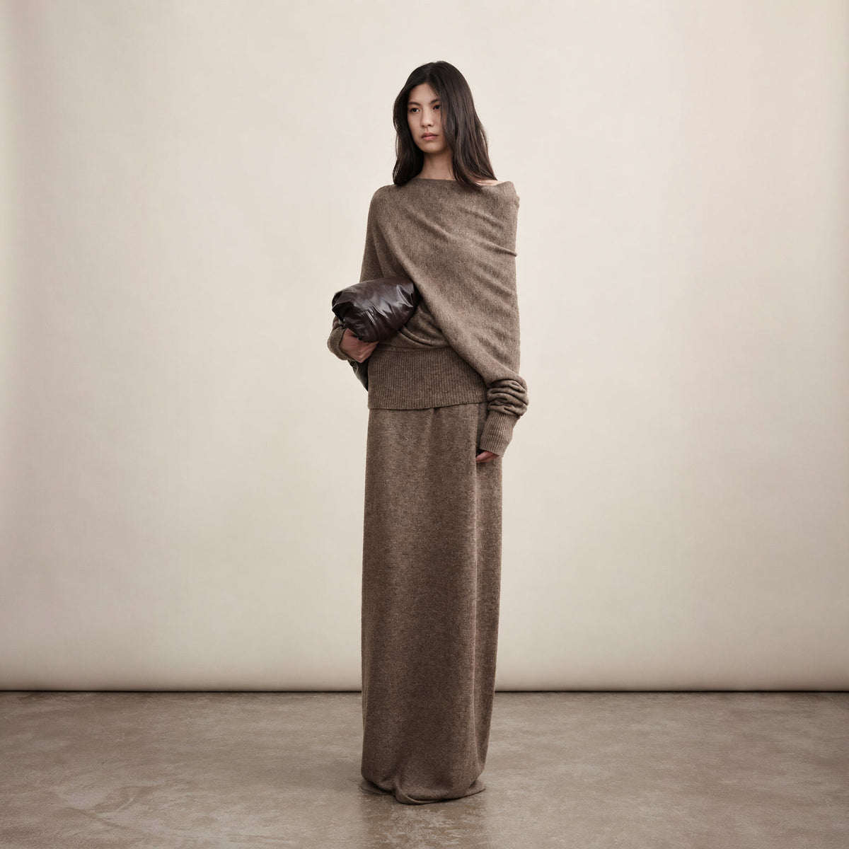Brown off-shoulder wool sweater and long skirt set, front view on model holding a clutch