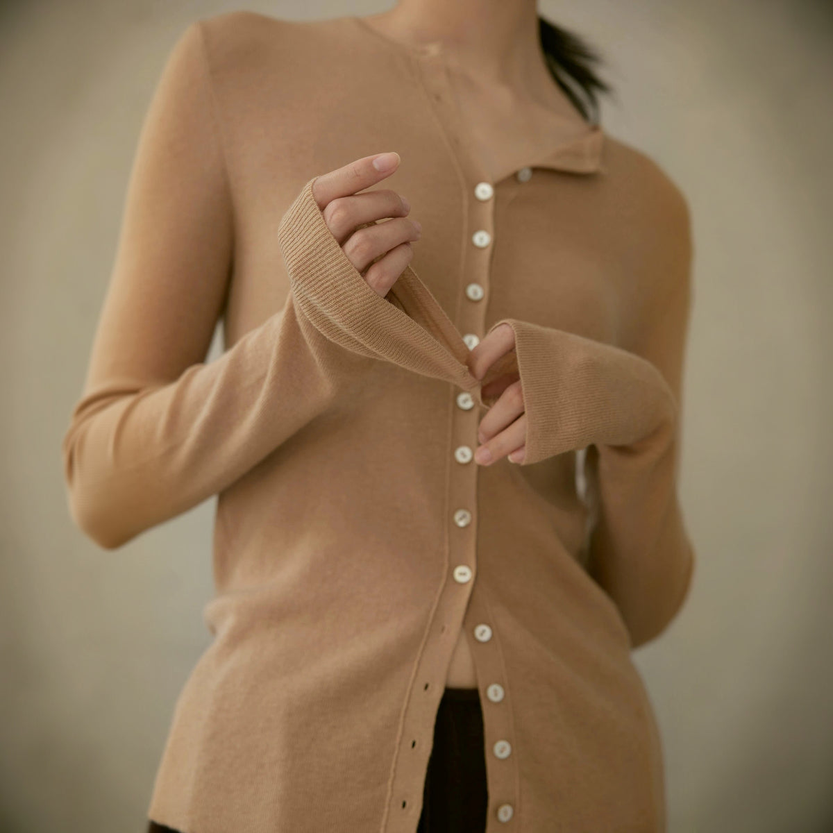 Wool cardigan in tan, close crop of the button placket and a ribbed sleeve cuff