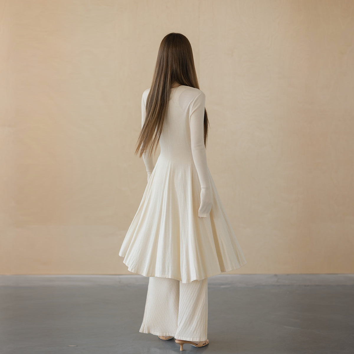 Cream tie-front cardigan, back view on model, flared panels falling from the waist to the hem