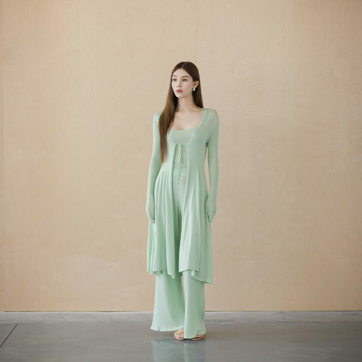 Sage green V-neck tie-front cardigan, front view on model, open below the bow at the base of the V