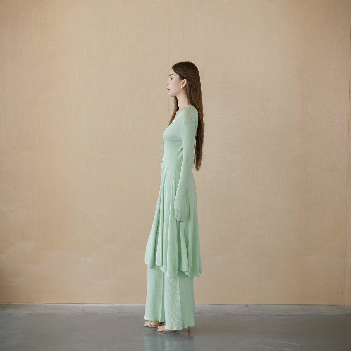 Sage green tie-front cardigan, side view on model, flared panelled hem and slim sleeve