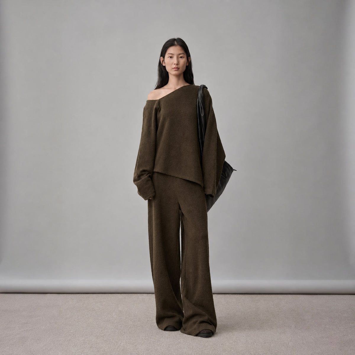 Wool sweater and wide-leg pants set in dark brown, front view on model, sweater slipping off one shoulder