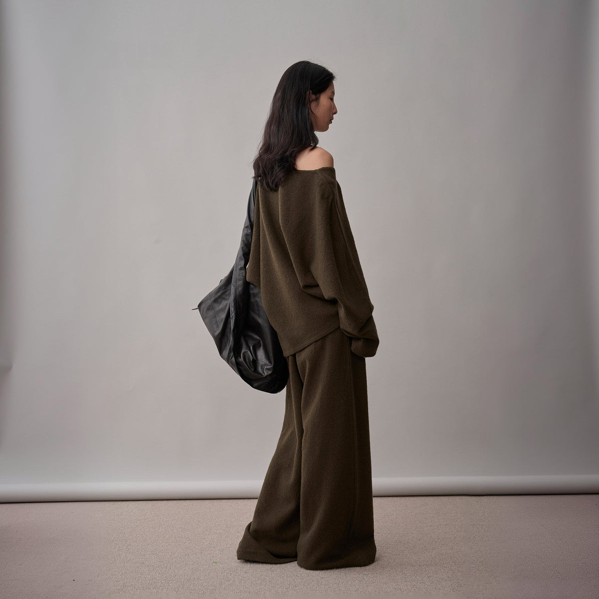 Dark brown wool sweater and wide-leg pants set, back view on model, sweater falling off one shoulder
