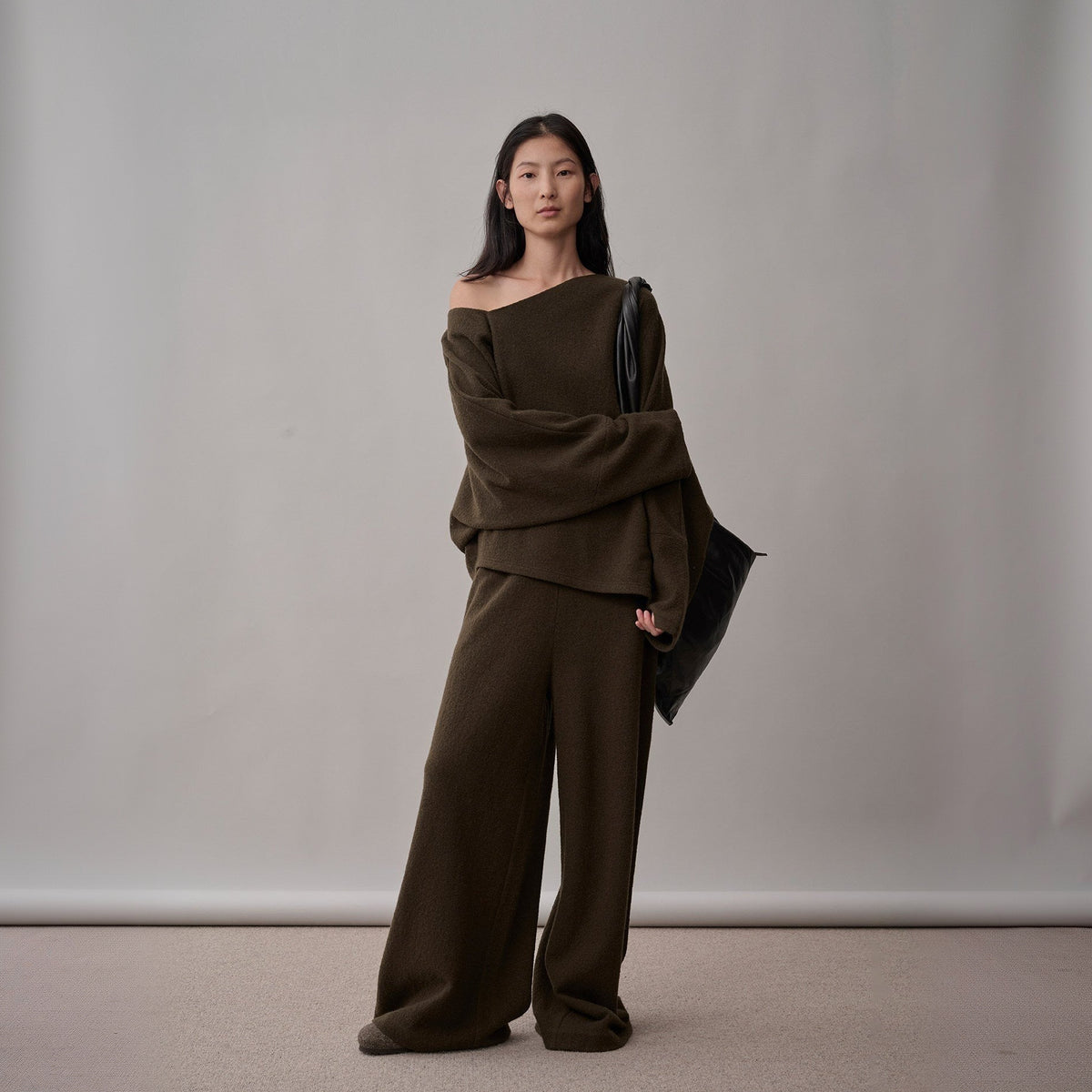 Dark brown wool sweater and wide-leg pants set, full-length front view on model, one arm folded across the body